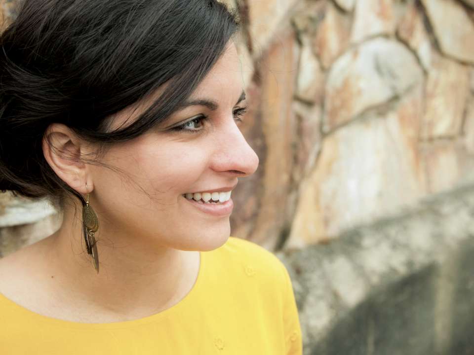 A woman in a yellow shirt standing in front of a wall