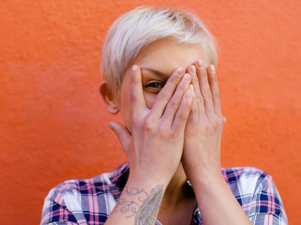 Blonde woman covering one eye with her hands