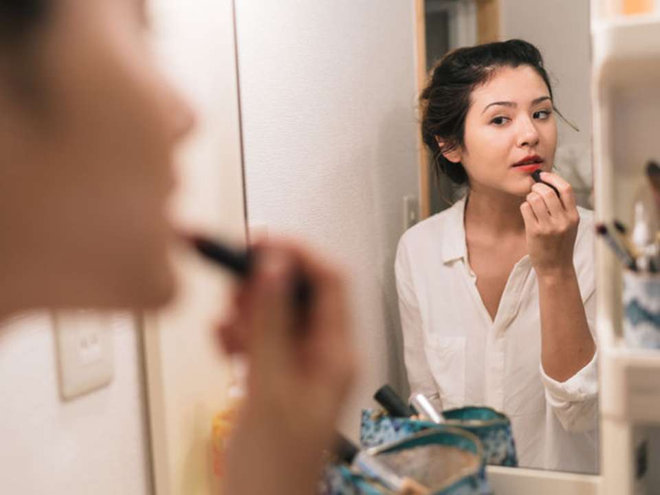 Woman-doing-makeup-in-mirror
