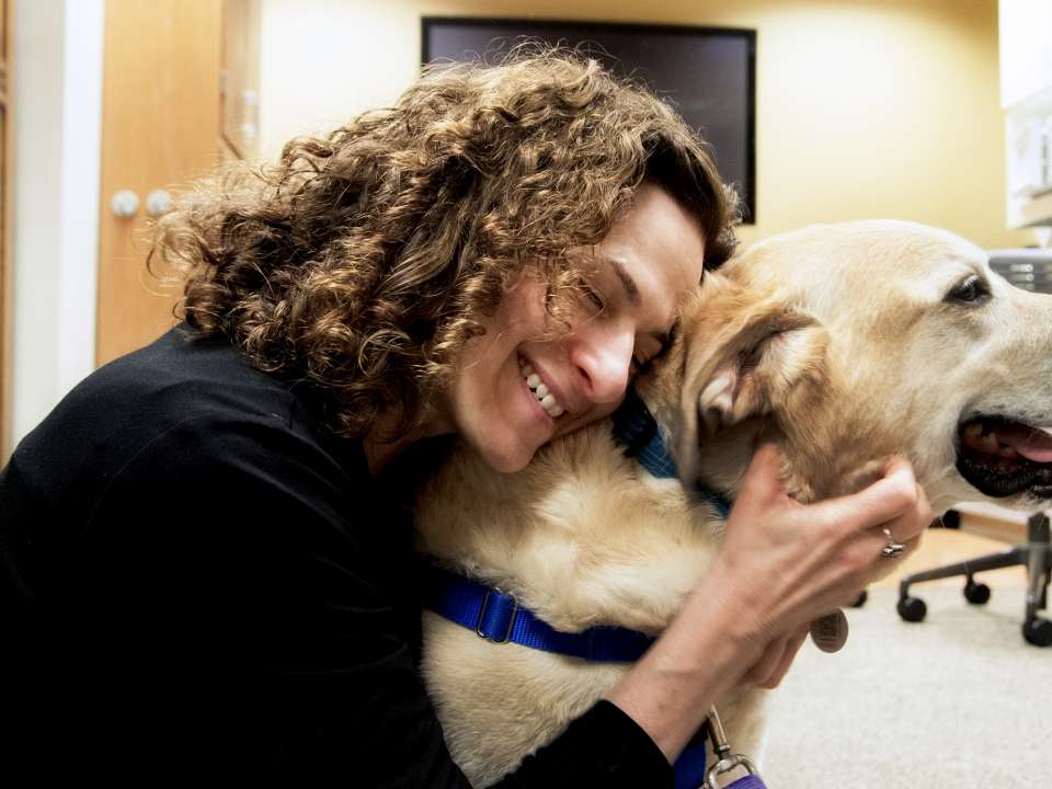 A woman hugs a dog during a pet therapy session.