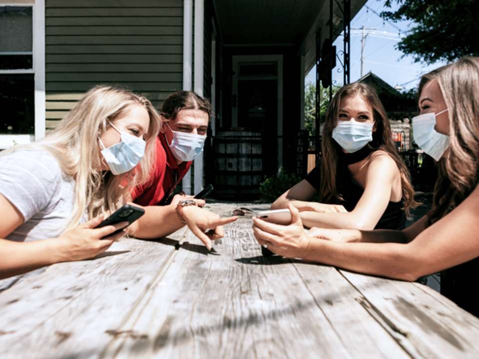Friends around picnic table with masks on