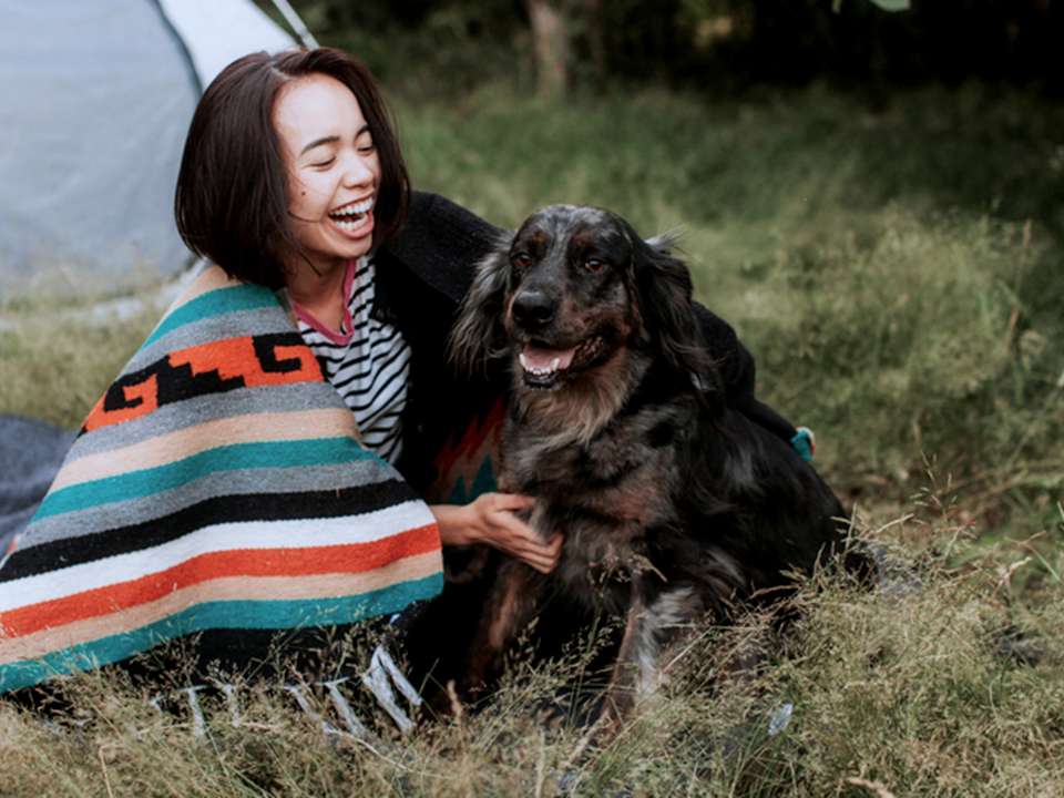 Woman cuddles her dog while camping outside