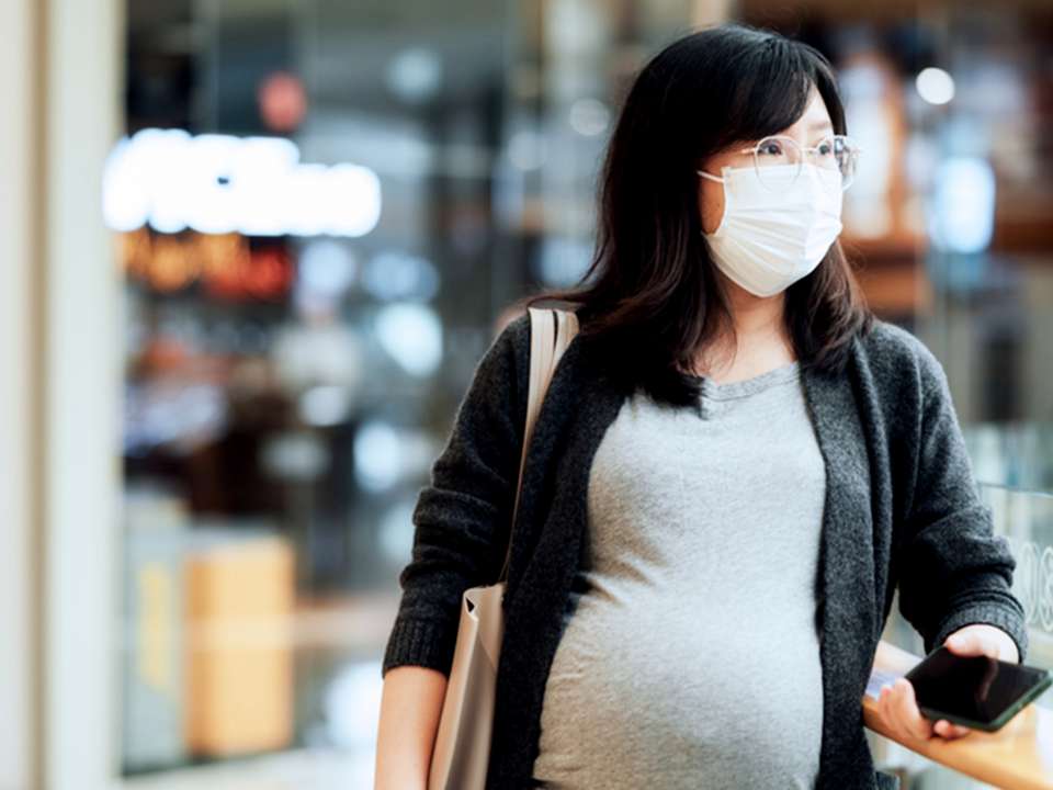 Pregnant woman wearing mask at mall.