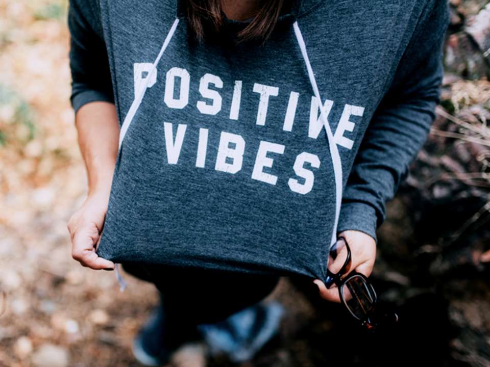 A person wears a sweatshirt that says 'positive vibes.'