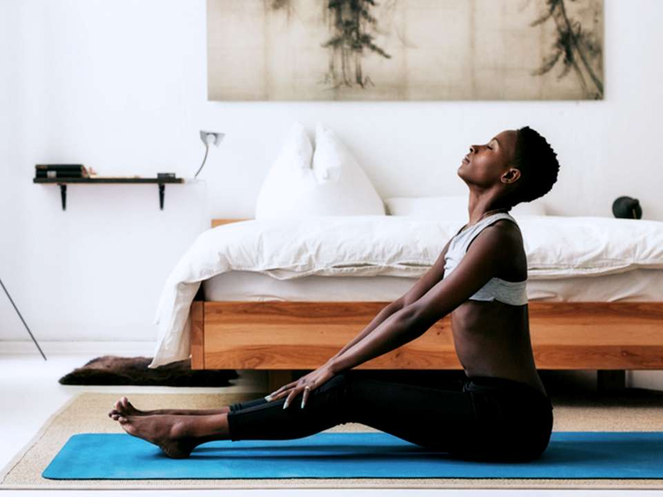 A woman sits on a yoga mat breathing deeply and relaxing.