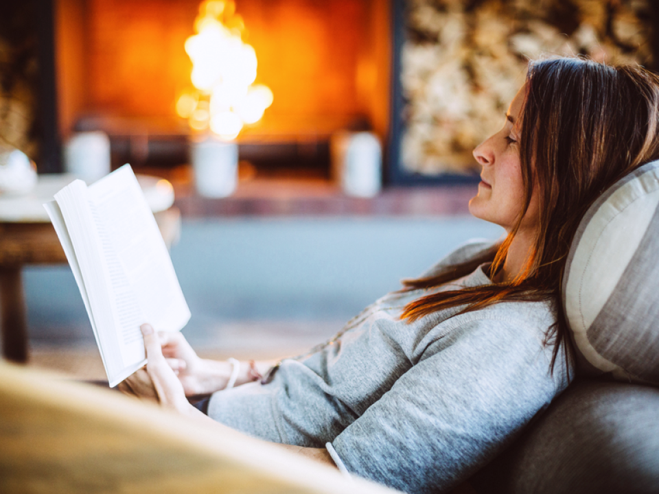 A woman reading next to a fire