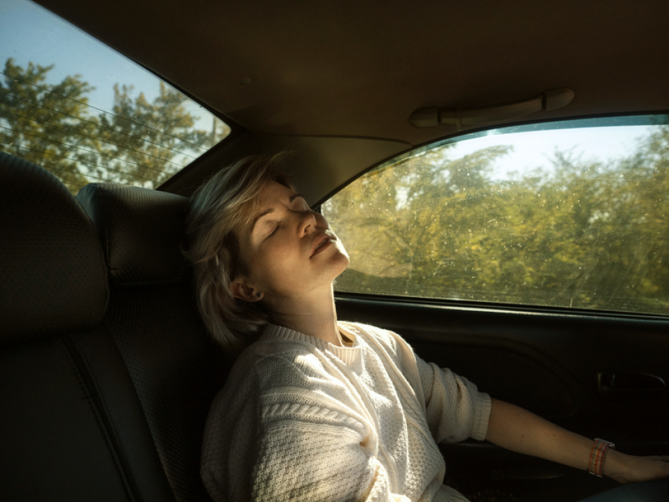 A woman sitting in the backseat of her car experiencing motion sickness