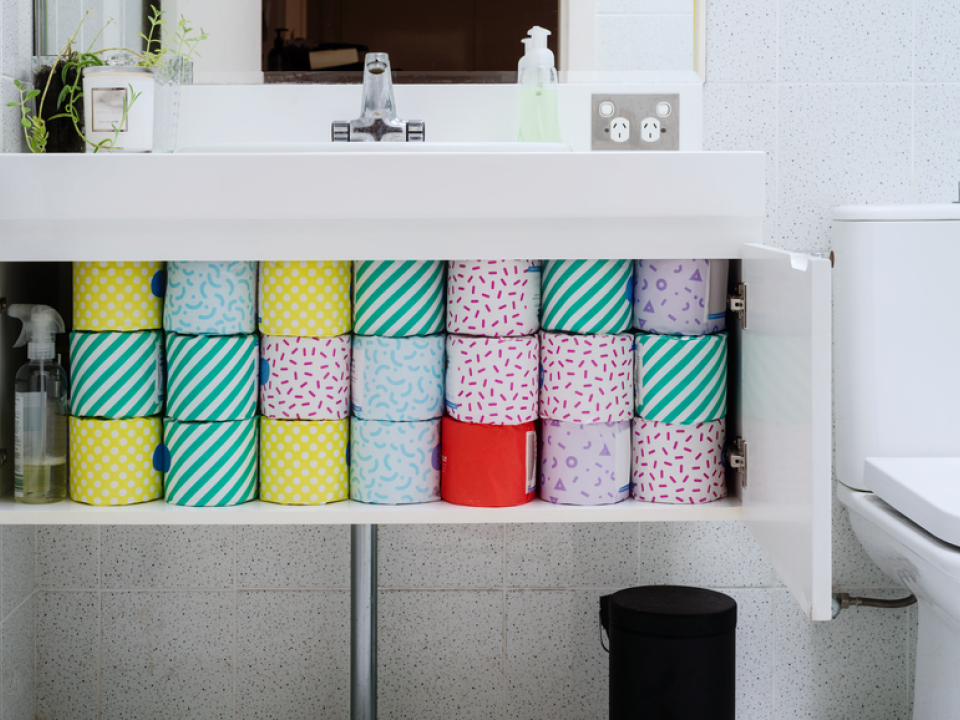 An image of an open bathroom cabinet that contains multiple rolls of toilet paper