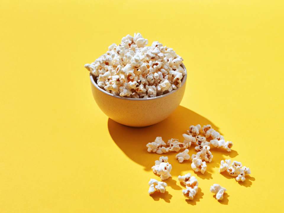 A bowl of popcorn on a yellow background.