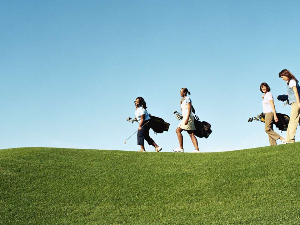 Four women walking on a golf course