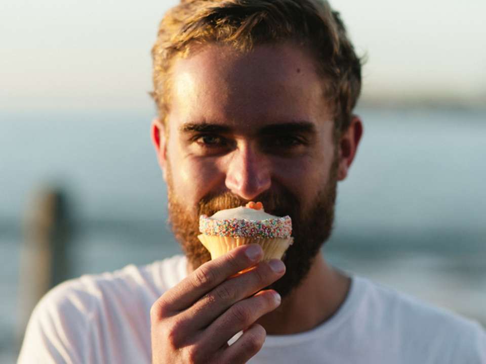man by the water holding a cupcake