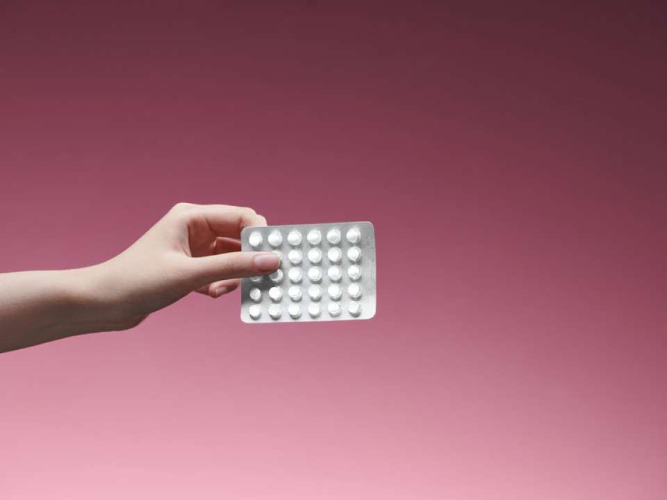 A photo of a hand holding birth control pills