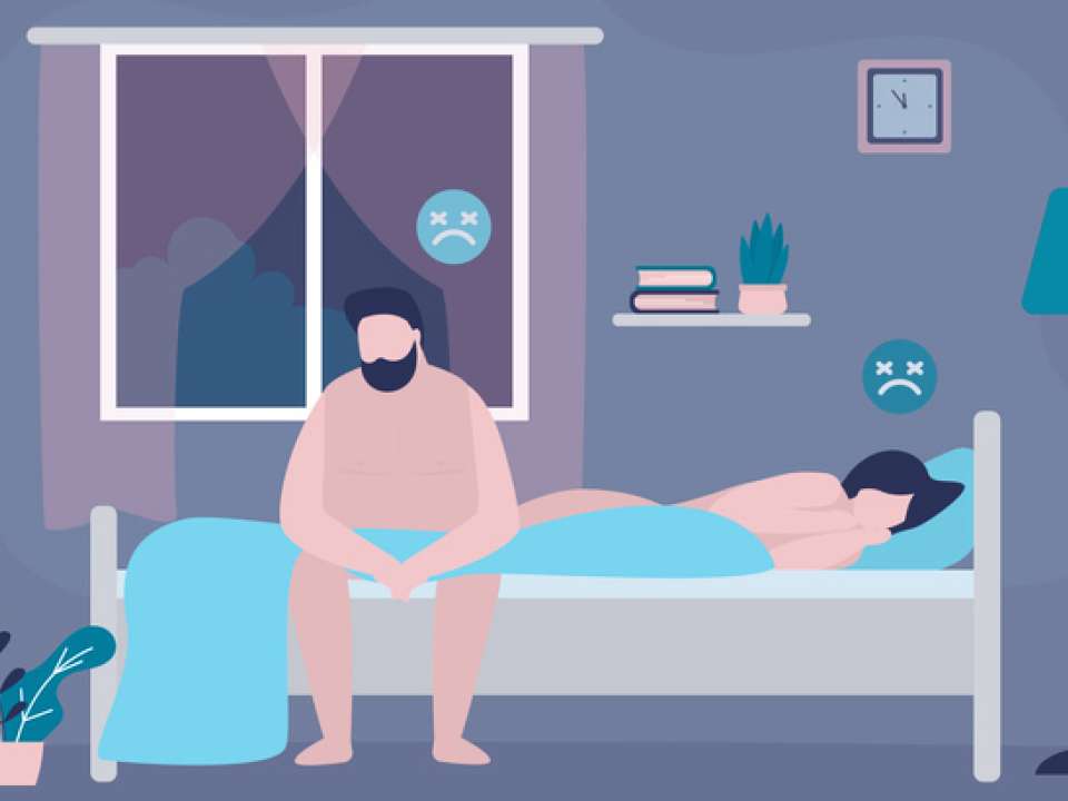 Man sitting on bed, woman lying in bed