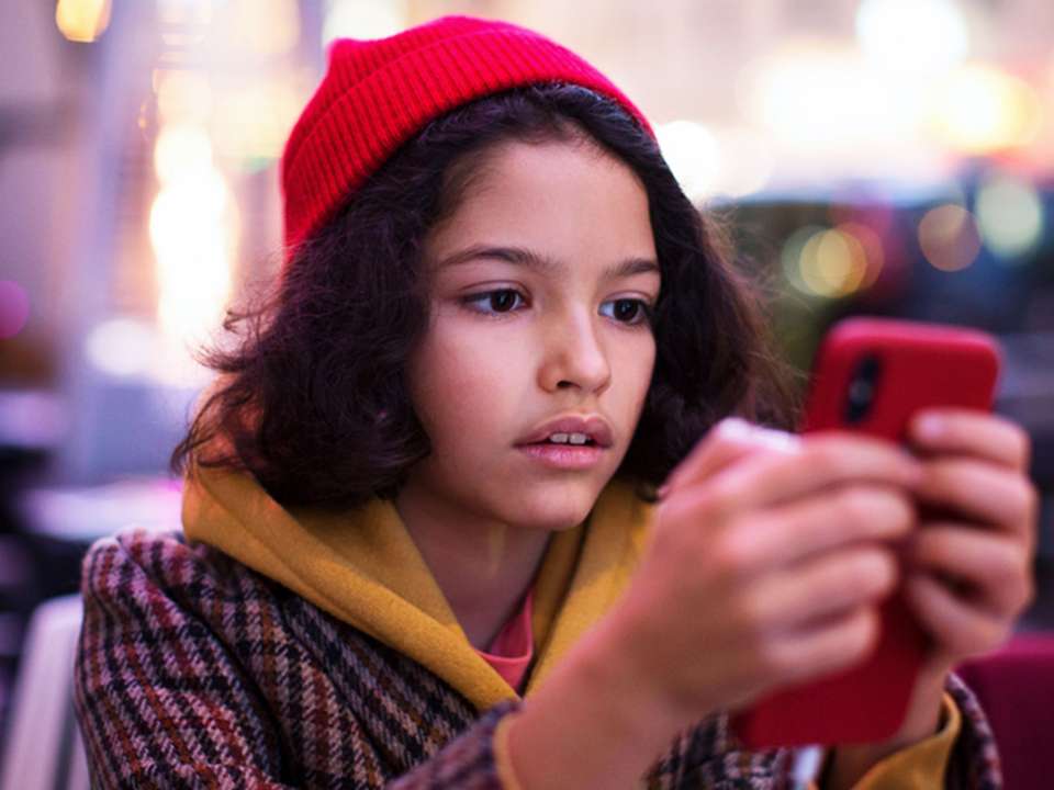 girl in red hat looking at her phone