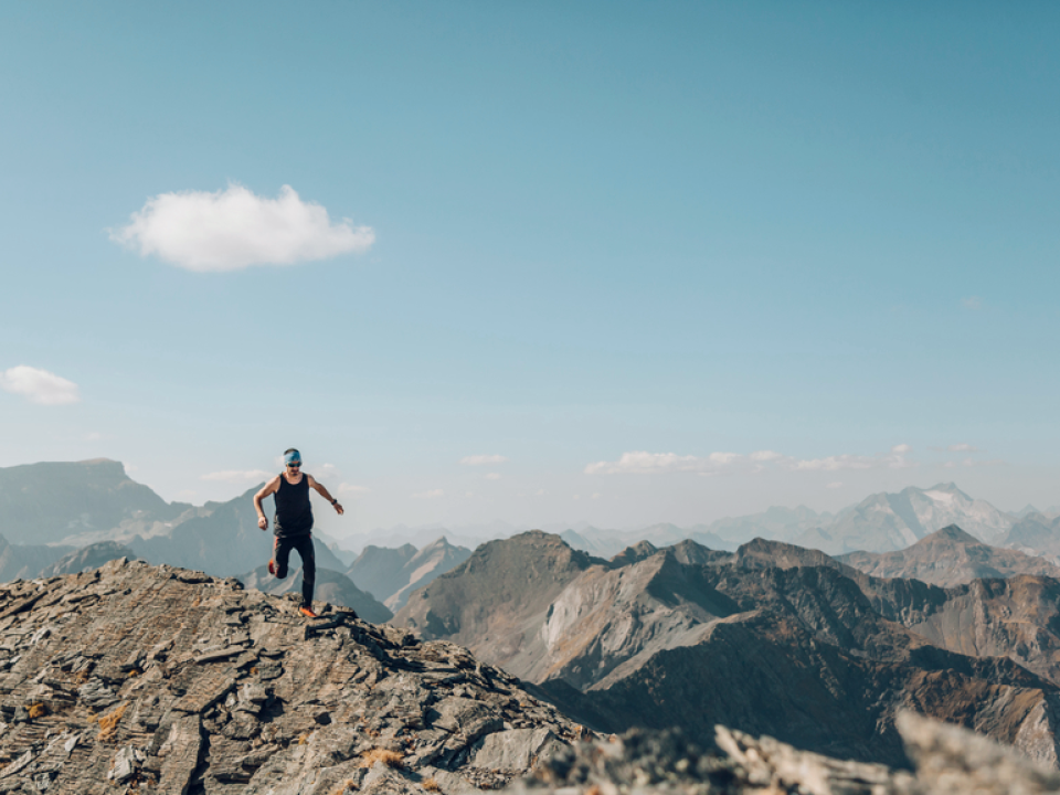 A photo of a man running along a mountain ledge