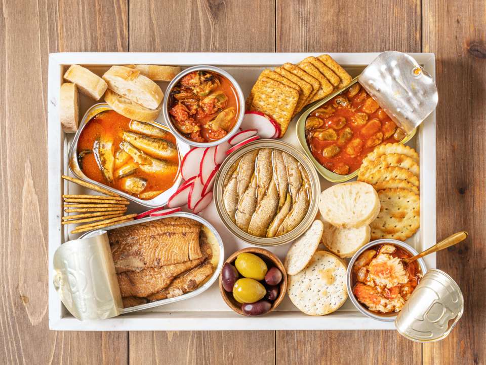 A spread of tinned fish, crackers and olives