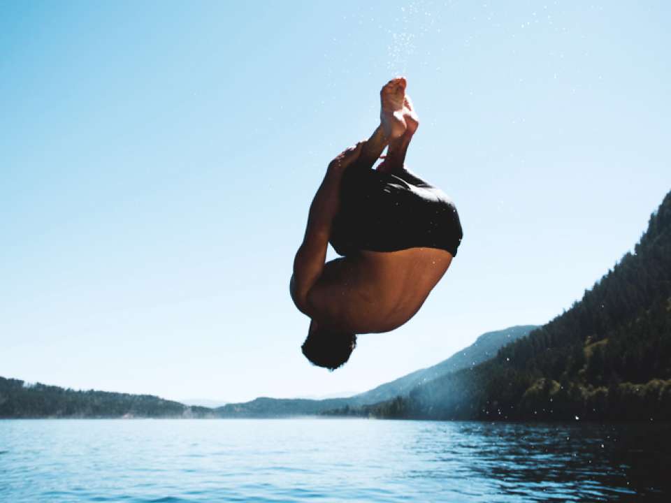 Man back-flipping into a lake 