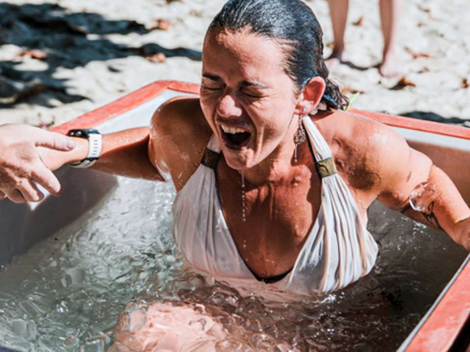 A woman does a cold plunge in a tub filled with ice.